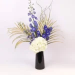 Heavenly Blooms: Flowers Artfully Arranged in Black Vase ? White Hydrangea, Blue Delphinium, Golden Sprayed Areca Palm Leaves