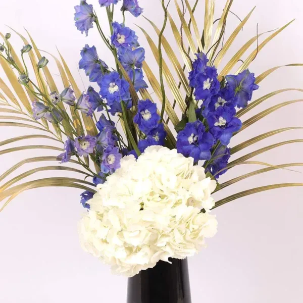 Heavenly Blooms: Flowers Artfully Arranged in Black Vase ? White Hydrangea, Blue Delphinium, Golden Sprayed Areca Palm Leaves